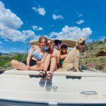 Boat renters and their dog on back of boat.